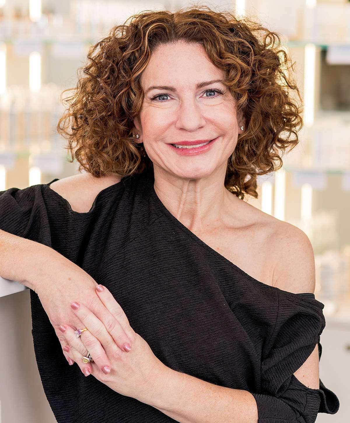 Woman with curly hair smiling in professional setting.