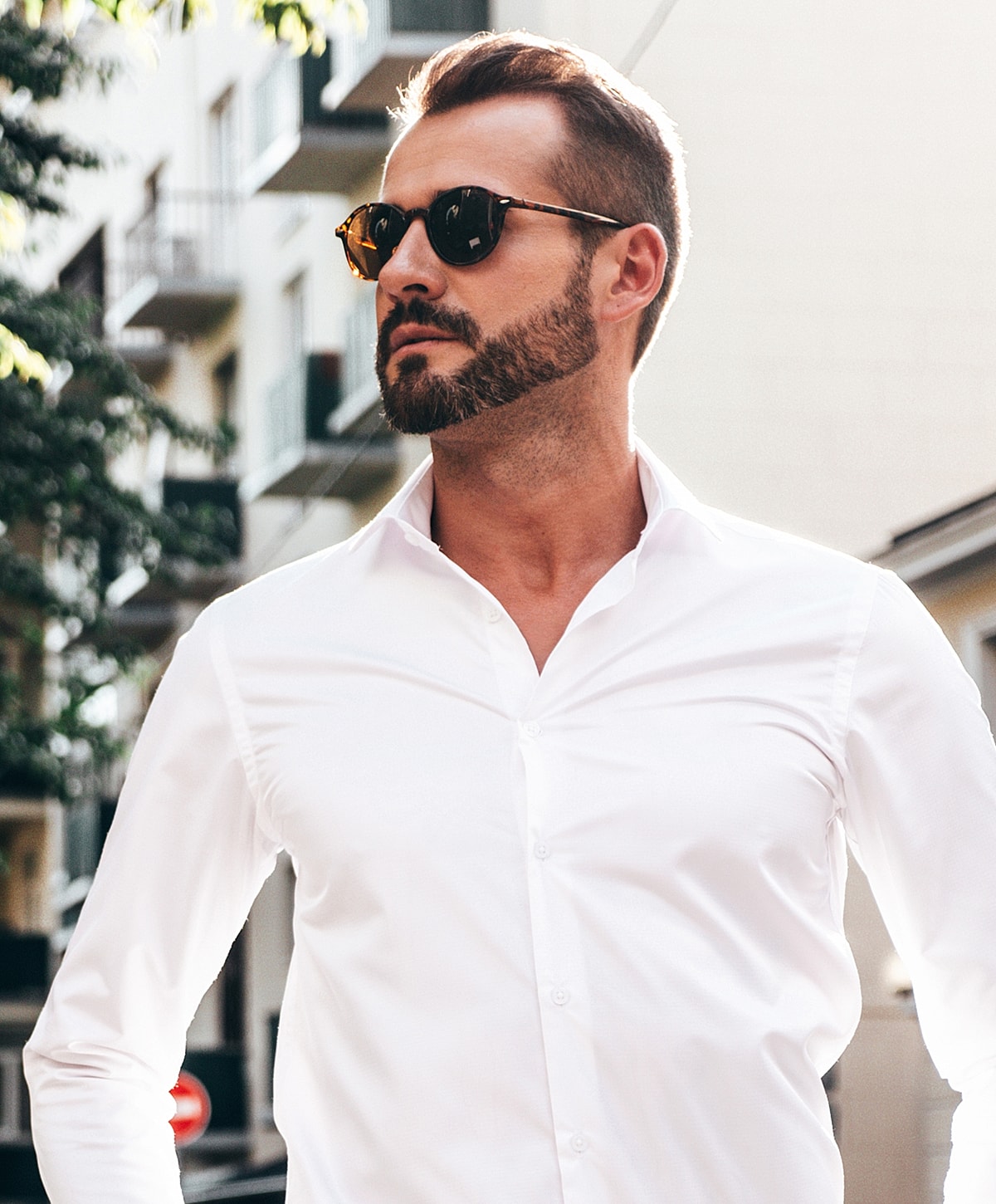 Man in sunglasses wearing a white shirt outdoors.