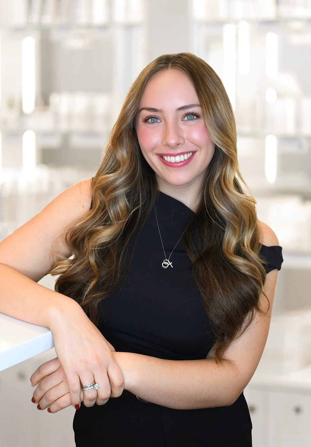 Smiling woman in black suit, skincare background.