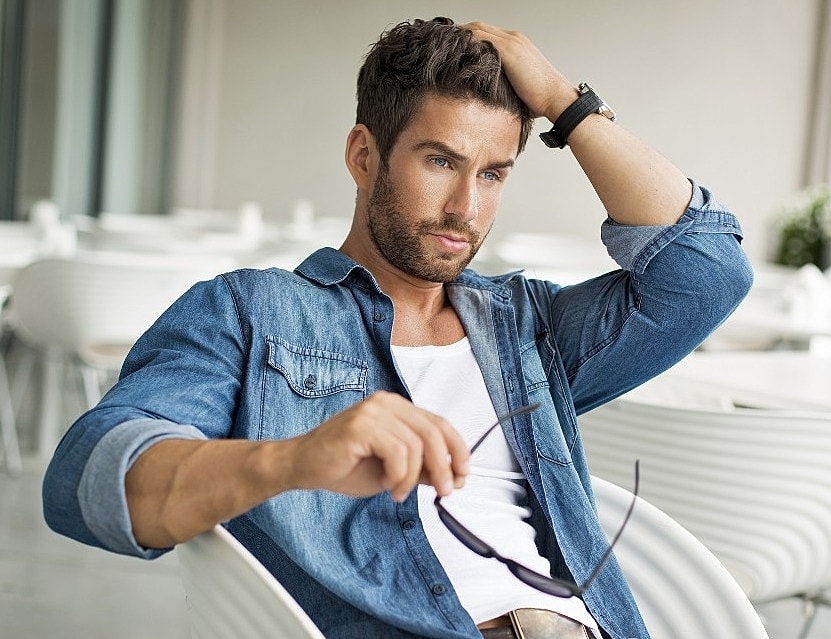 Man in denim shirt thinking with sunglasses.