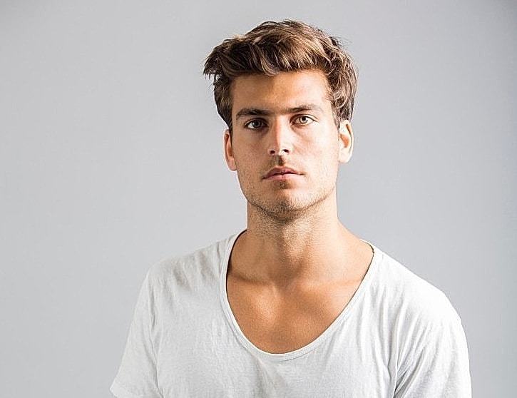 Young man in a white shirt, neutral background.