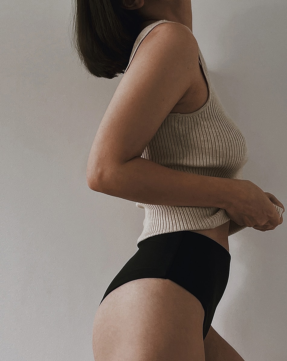 Woman in tank top and high-waisted bottoms.