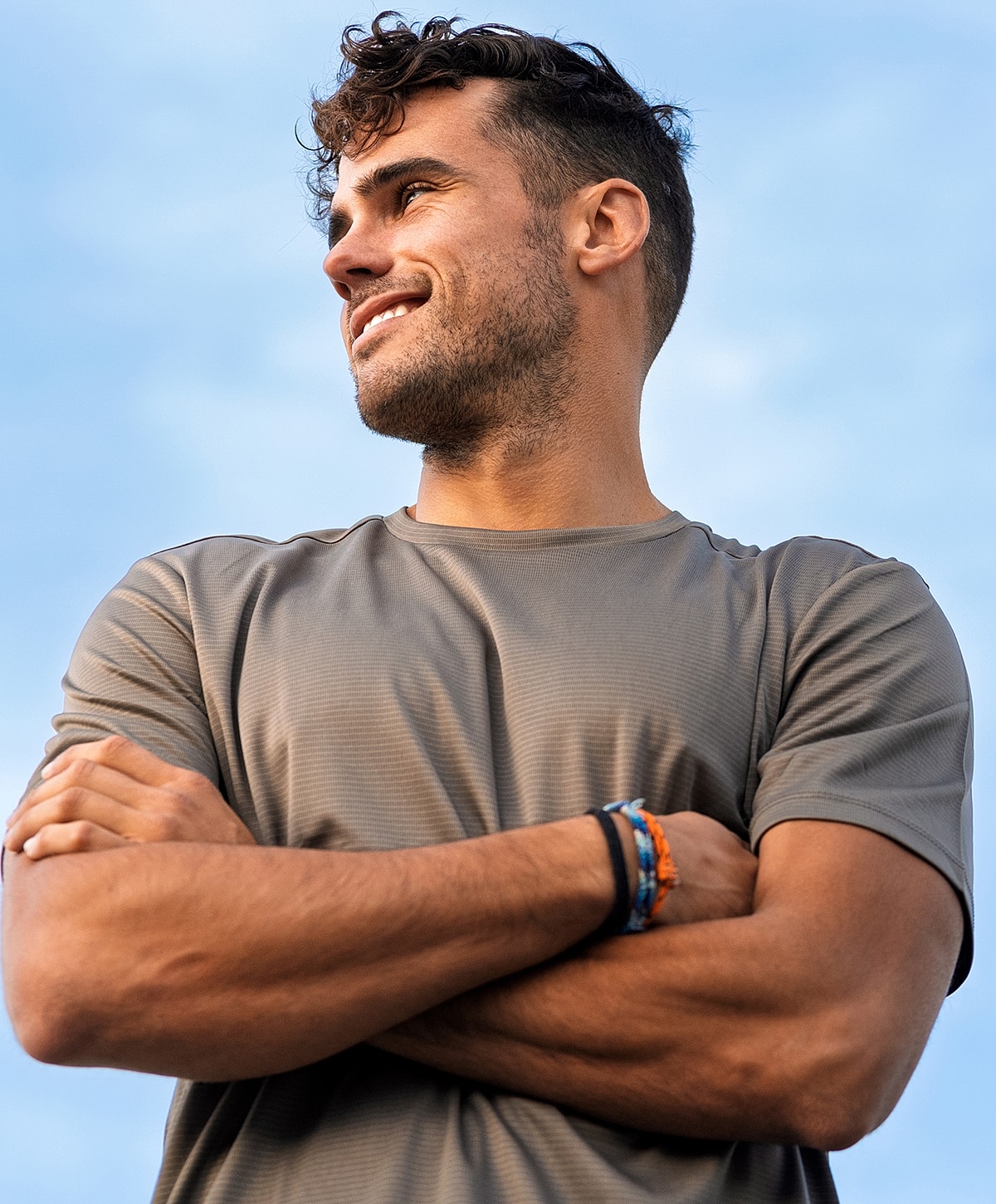 Smiling man with arms crossed against blue sky