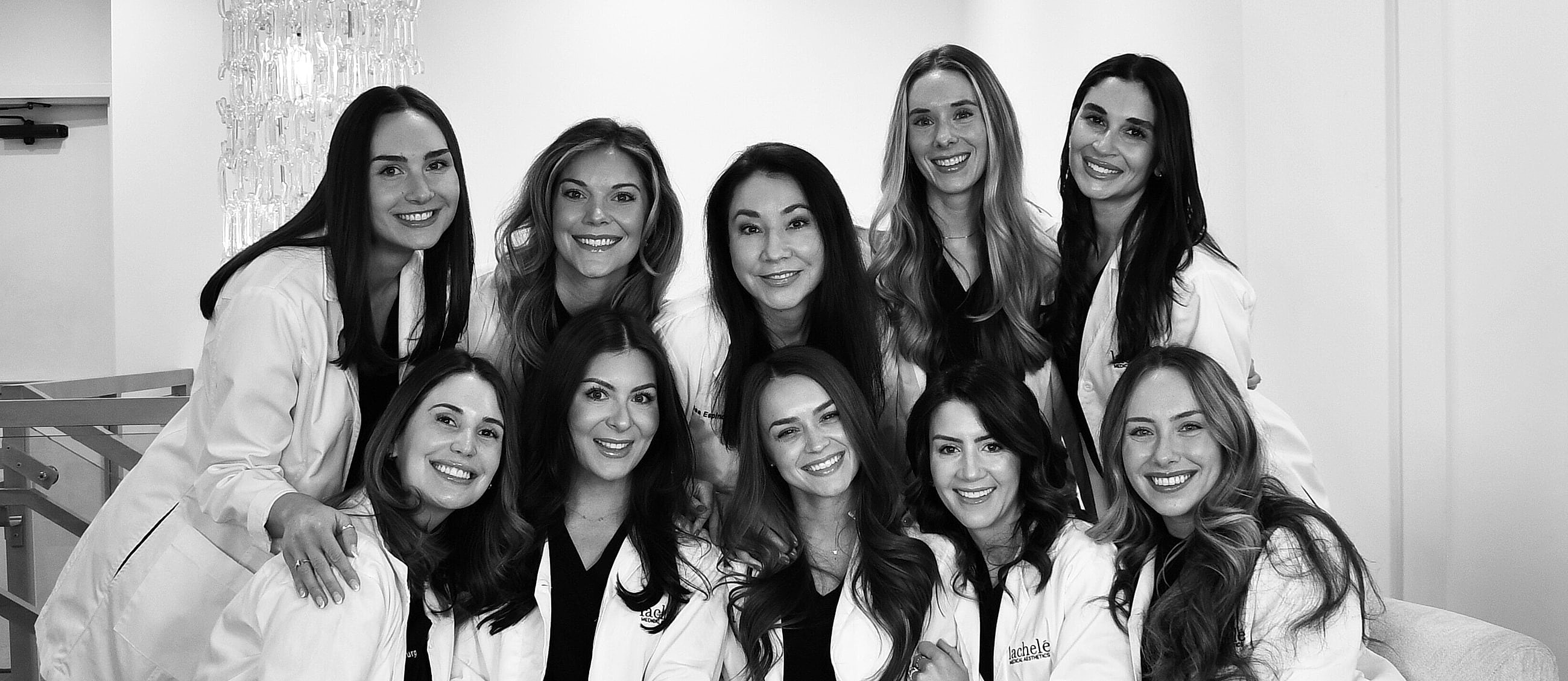 Three professionals in medical attire smiling together.