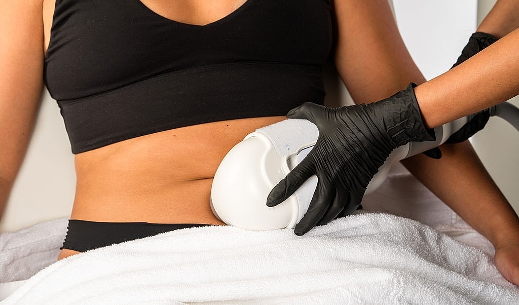 Woman in elegant black dress posing on couch.