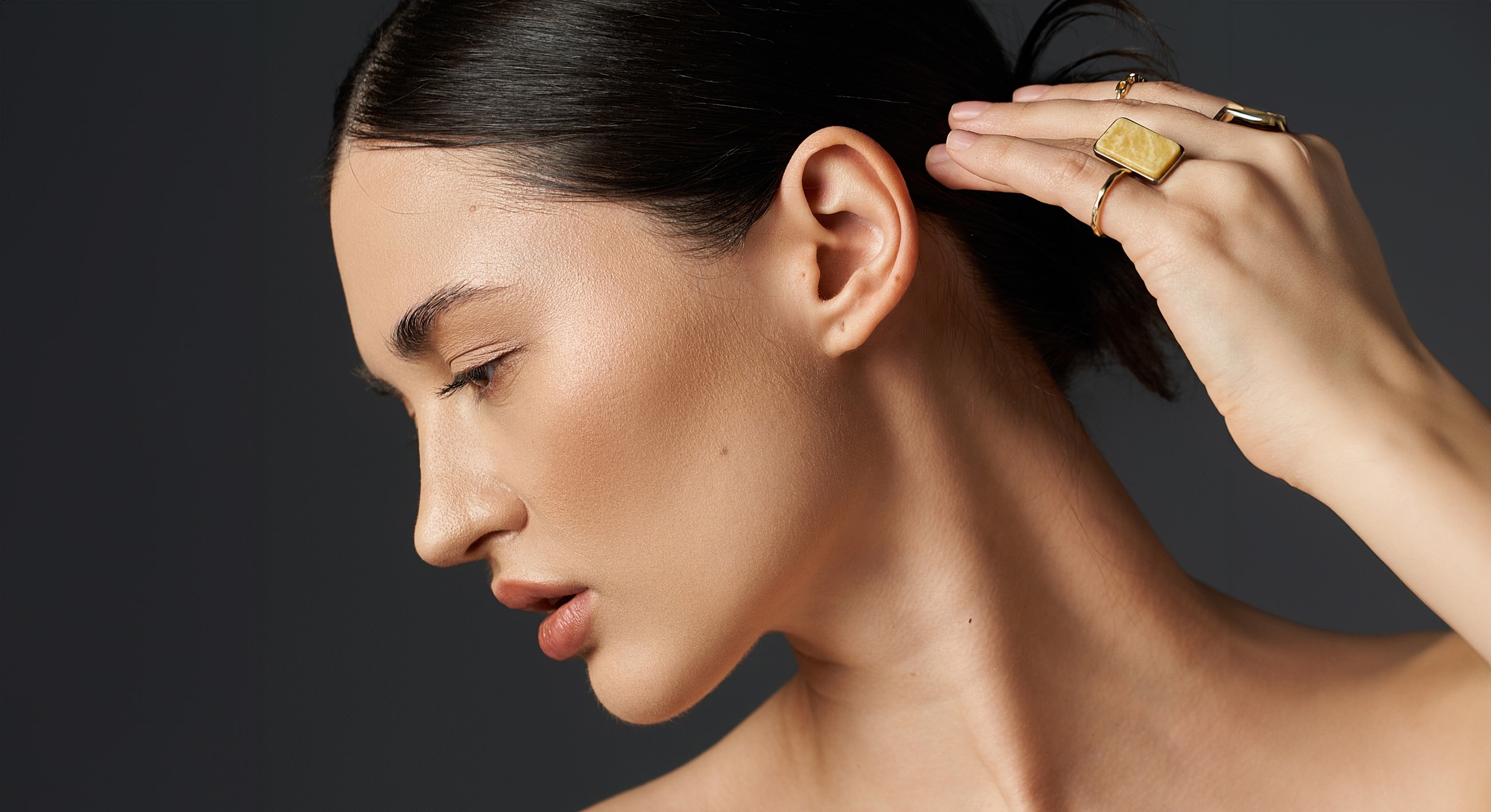 Profile of a woman adjusting her hair.