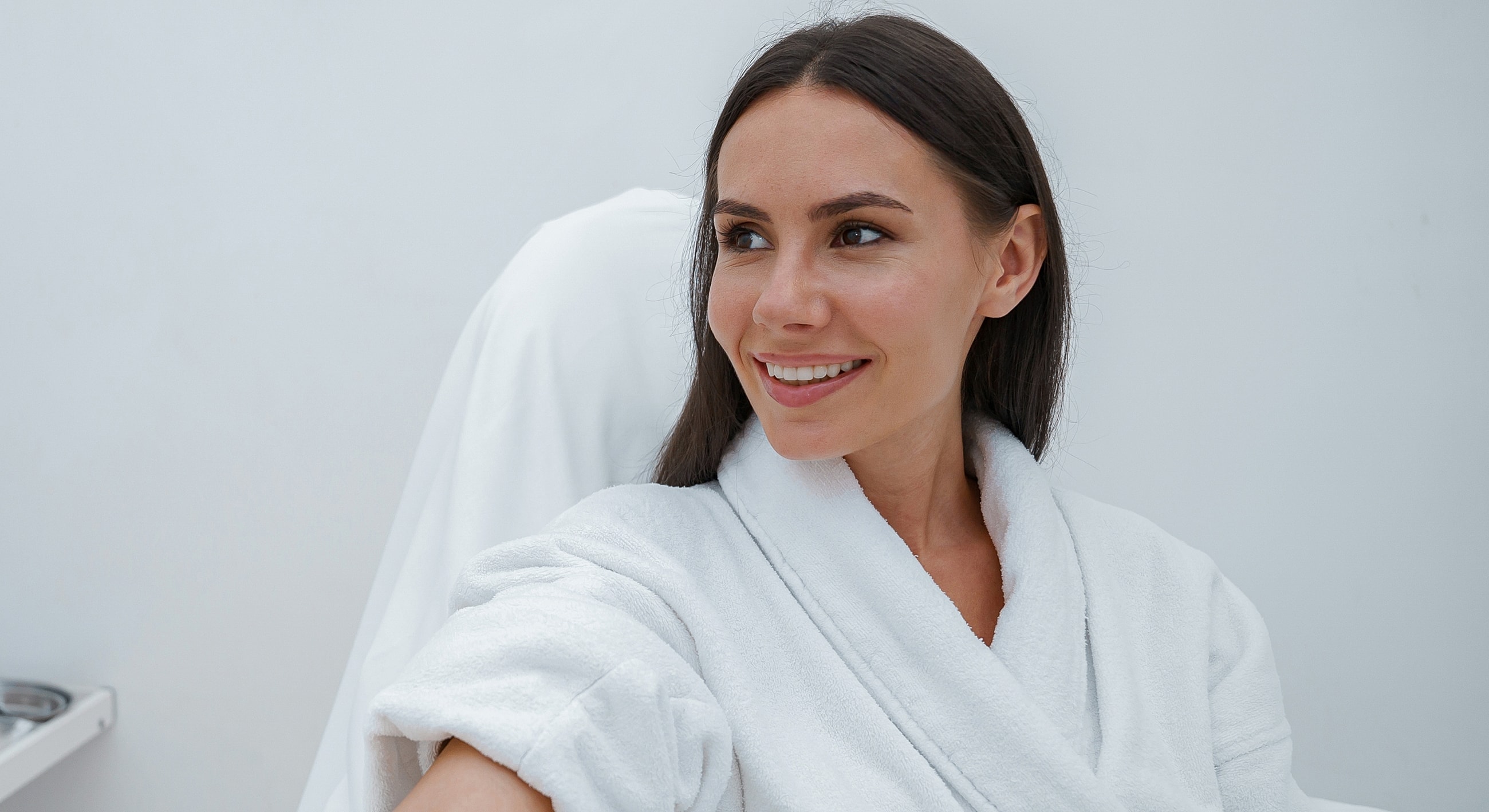 Smiling woman in a spa robe, relaxed atmosphere.