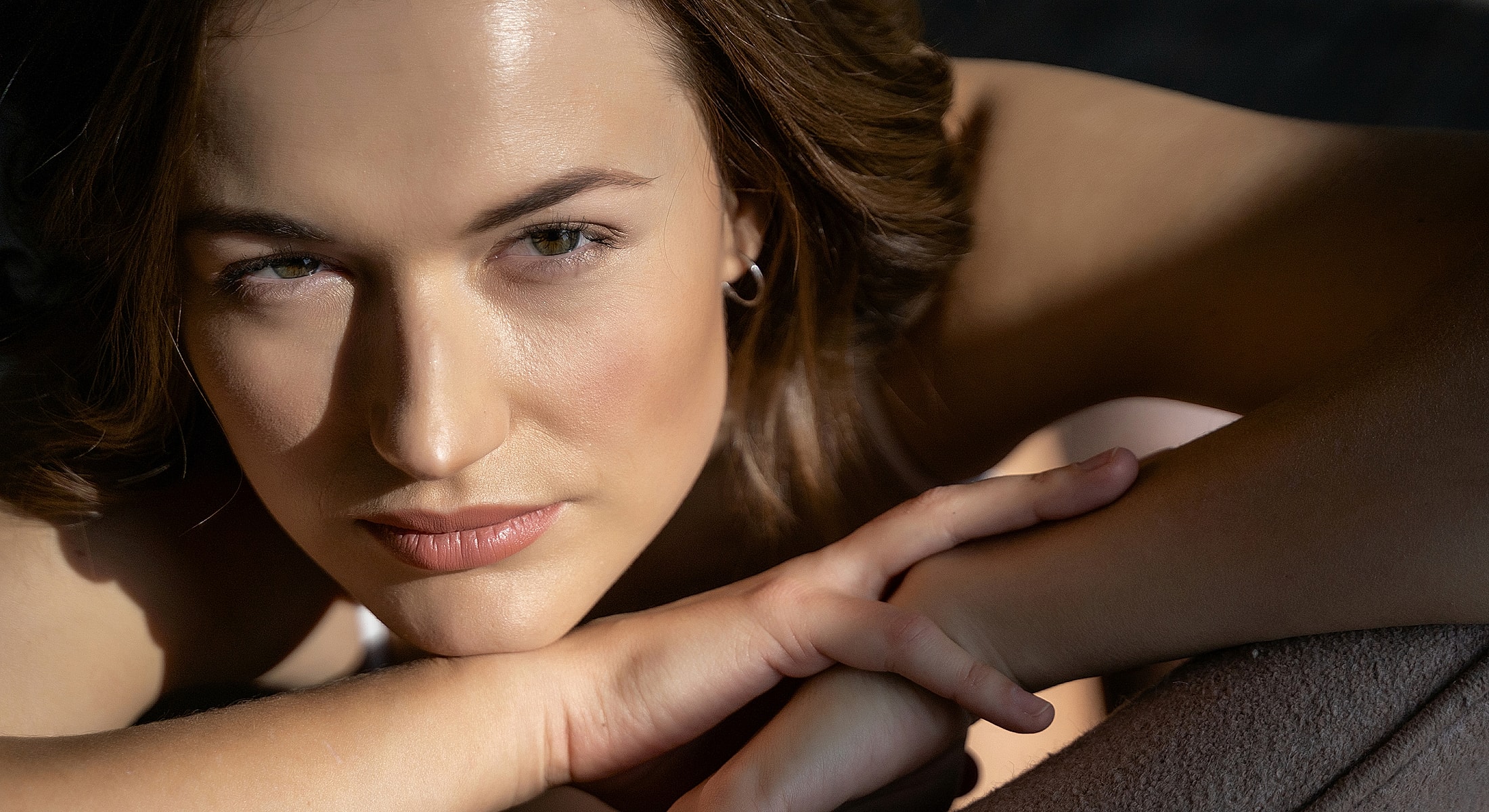Person resting with hands beneath chin, contemplative expression.