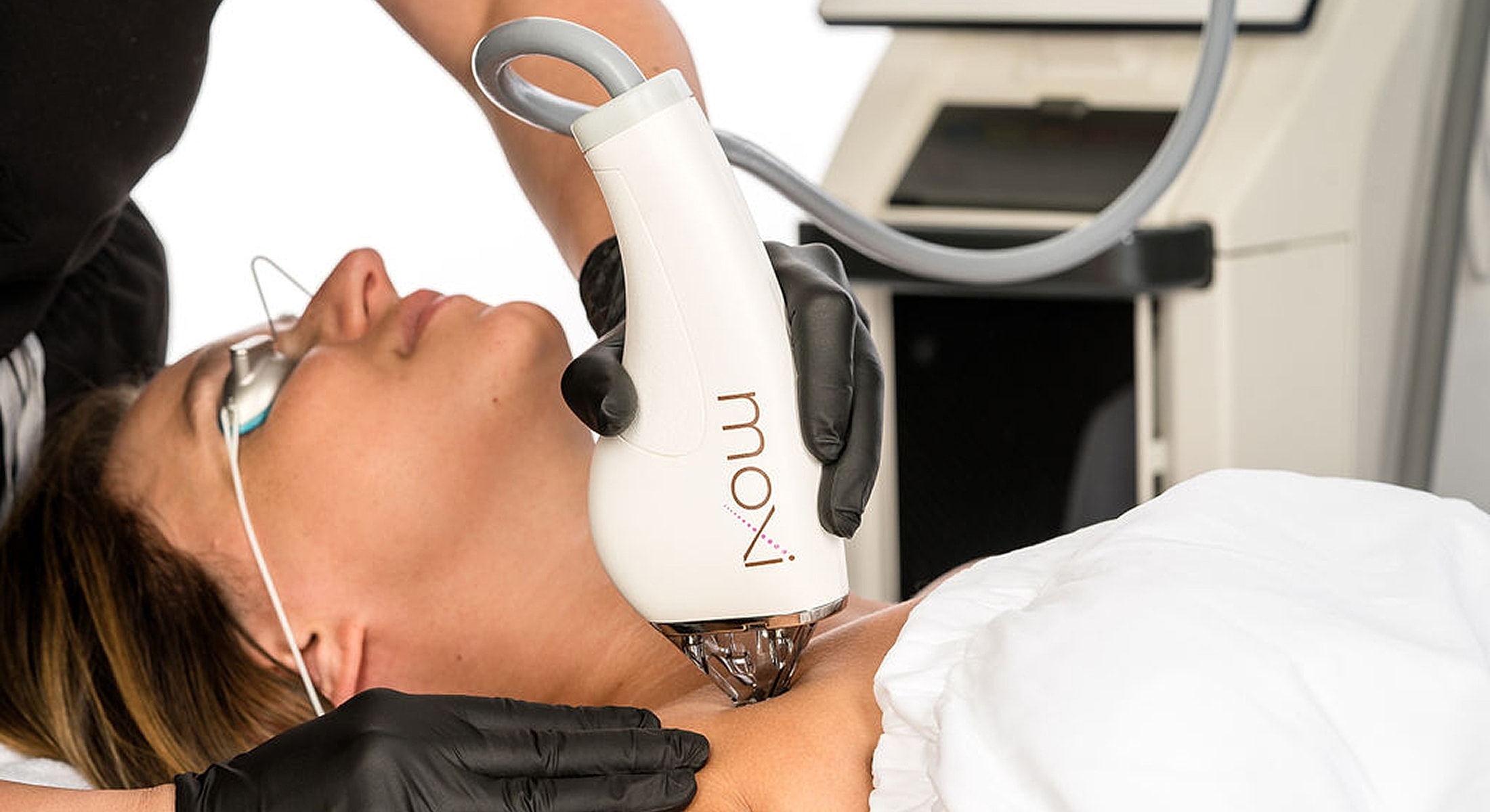 Woman receiving skin treatment with laser device.