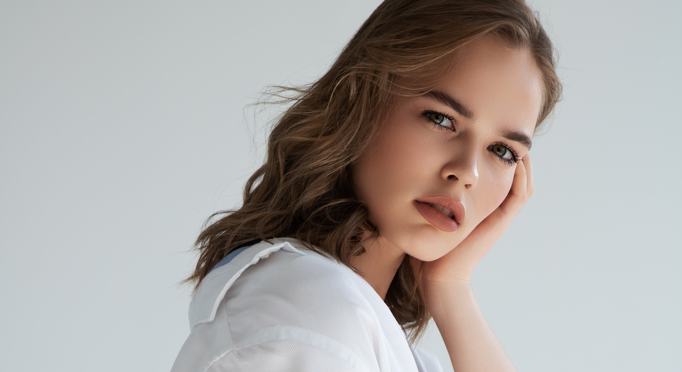 Young woman in thoughtful pose against plain background