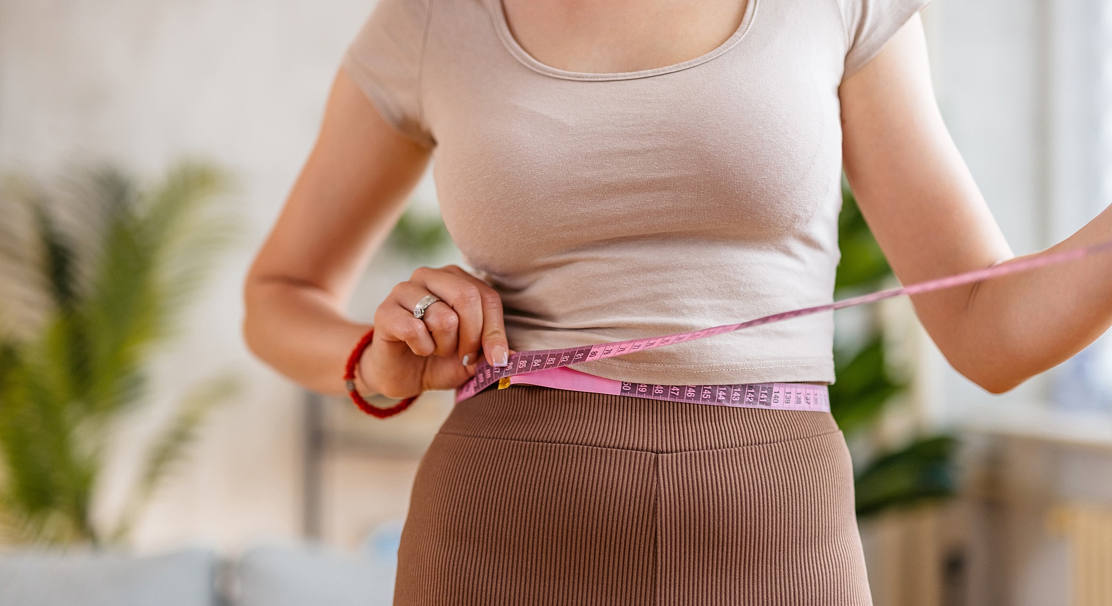 Woman measuring waist with a tape measure.
